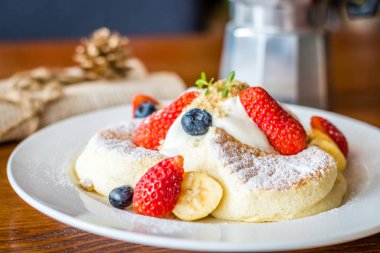 Taze çilek, Berry, muz, krem ve akçaağaç şurubu ile meyve salatası Souffle pancake