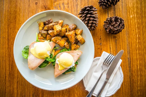 Organic Egg Benedict Poached egg, smoked turkey ham, baby spinach, creamy hollandaise sauce, fluffy brioche bun and spicy roasted potato. — Stock Photo, Image