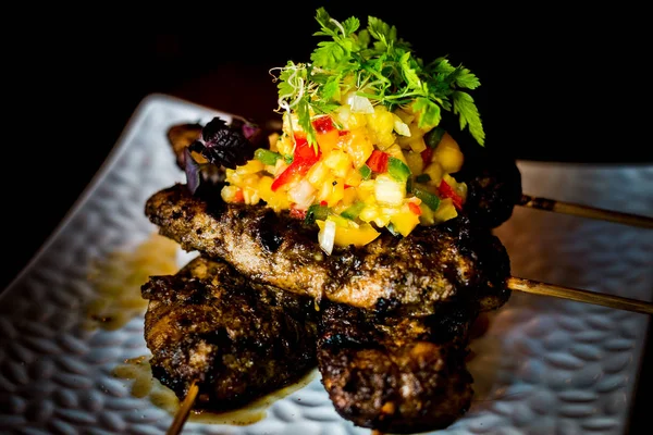 Char-grilled jerk marinated chicken tenders in skewers with fruit salsa on top — Stock Photo, Image