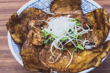 buta Don teriyaki soslu siyah domuz ızgara ve pirinç bir yatakta dilimlenmiş turp ve soğan ile servis