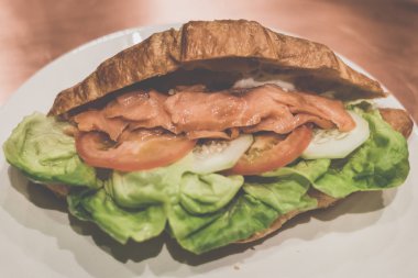 Beyaz porselen plaka üzerinde füme slamon ve marul ve domates ile Kruvasan