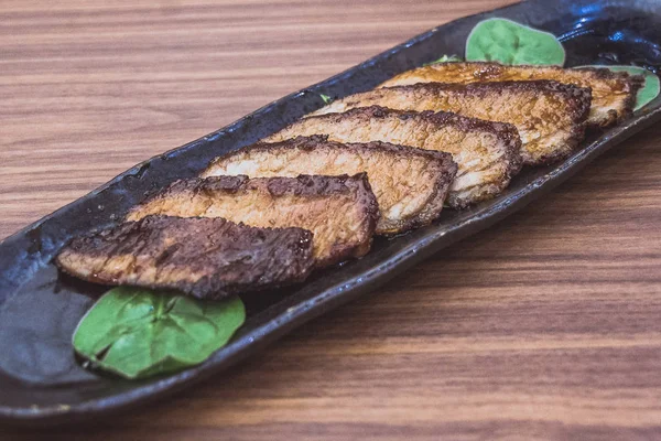 Côté plat Kurobuta Hoho Yaki Grillé Iberico Jowl de porc servi sur des feuilles d'épinards — Photo