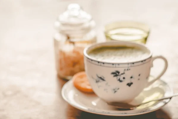 green tea matcha soy latte in a china cup with brown sugar and a glass of water on the side