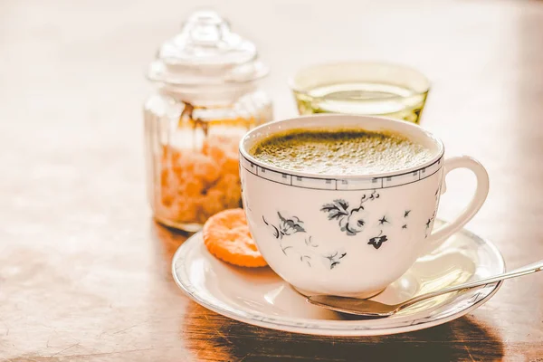 green tea matcha soy latte in a china cup with brown sugar and a glass of water on the side