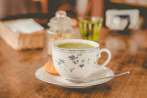 green tea matcha soy latte in a china cup with brown sugar and a glass of water on the side