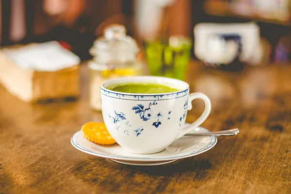 green tea matcha soy latte in a china cup with brown sugar and a glass of water on the side