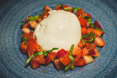 Çilek ve San Marzano Domates ile Burrata beyaz bir çin plaka sıyrık üzerinde servis
