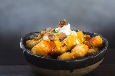 Gevrek tater tots acımasızca baharatlı jalapeno peynir sosu, akçaağaç sırlı pastırma ve ekşi krema içinde ıslatılmış. Acı sos bir sıçrama ile bitmiş