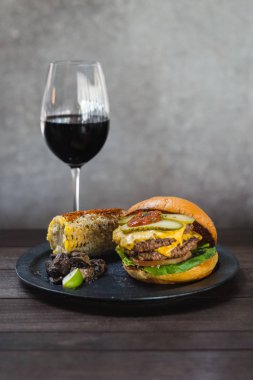 Amerikan burgeri. Bir çift wagyu yağ ve chuck karışımı börek topuzuniçinde börek ve pastırma ketçap karışımı. Meksika mısırve sote kekik mantar ile servis.