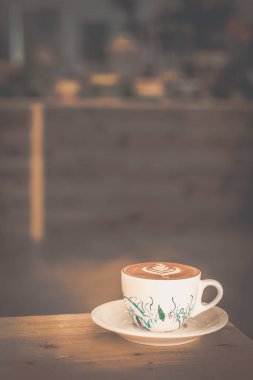 bir kafede bir porselen fincan ve tabak yaprak tasarım latte sanat ile cappucino