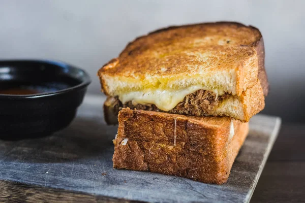 Braised Shortrib Grilled Cheese.  A blend of gruyere and taleggio cheese sandwiched between buttery artisanal white loaves.  Stuffed with juicy, braised beef shortrib.