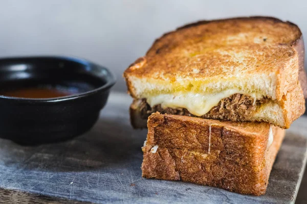 Braised Shortrib Grilled Cheese.  A blend of gruyere and taleggio cheese sandwiched between buttery artisanal white loaves.  Stuffed with juicy, braised beef shortrib.