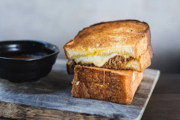 Braised Shortrib Grilled Cheese.  A blend of gruyere and taleggio cheese sandwiched between buttery artisanal white loaves.  Stuffed with juicy, braised beef shortrib.