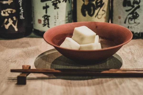 Cubos de bolo de peixe japonês de madeira dispostos e servidos em uma tigela vermelha em um izakaya japonês tradicional — Fotografia de Stock