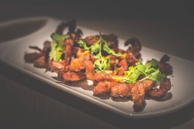 Derin kızarmış tay domuz boyun maydanoz ve sarımsak beyaz bir porselen plaka üzerine daldırma sosu ile servis