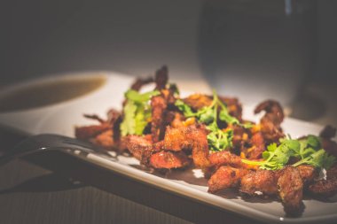 Derin kızarmış tay domuz boyun maydanoz ve sarımsak beyaz bir porselen plaka üzerine daldırma sosu ile servis