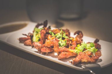 Derin kızarmış tay domuz boyun maydanoz ve sarımsak beyaz bir porselen plaka üzerine daldırma sosu ile servis