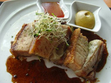 Kalın koyu sos lu rosto domuz eti ve biber sosu ve hardal ile servis edilir