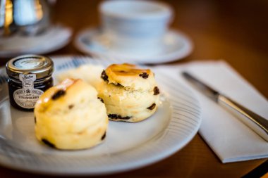 tarafında meyve reçeli ile beyaz bir çin plaka üzerinde üç kuru üzüm çörekler