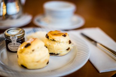 tarafında meyve reçeli ile beyaz bir çin plaka üzerinde üç kuru üzüm çörekler