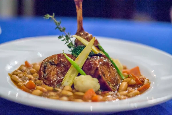 Portugiesisches Kaninchen mit weißen Bohnen und Karotteneintopf in einem weißen Porzellangericht serviert — Stockfoto