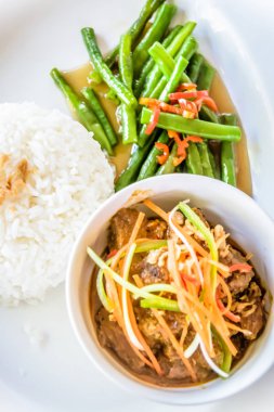 Üzerine jülyen soslu havuç, kızarmış fasulye ve beyaz pirinç ile servis edilen sığır eti.