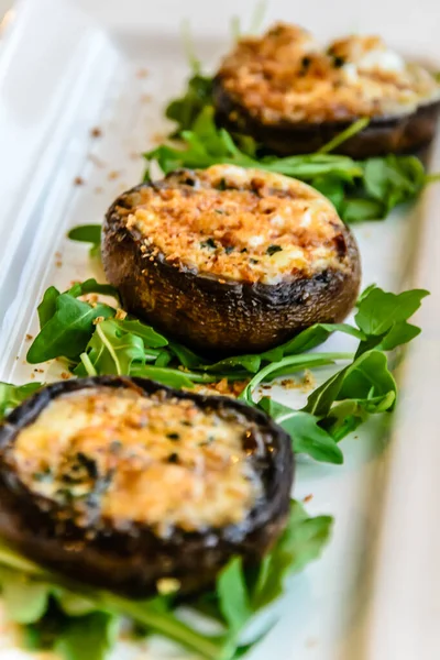 Vegetarian starter of grilled portobello mushrooms with cheese, herbs and garnished with rucola rocket leaves — Stock Photo, Image