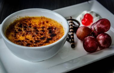 Creme brulee taze krema, tatlı kiraz, çikolata ve üzümle servis edilir.