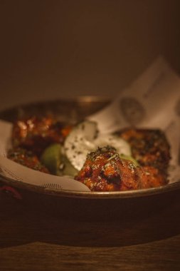 Sambal Wings ızgara tavuk kanadı sambal sosuna batırılmış salatalık ve biraz kalamansi ile süslenmiş.