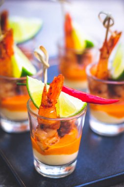 Kreol soslu karides şişi ve krem peynir sosu ve limon dilimi shot bardağında servis edilir.