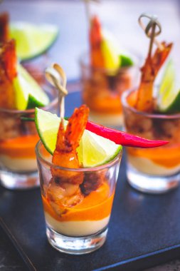 Kreol soslu karides şişi ve krem peynir sosu ve limon dilimi shot bardağında servis edilir.