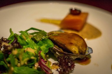 Kiralanmış deniz kulağı ve yanında salata olan somon kübü.