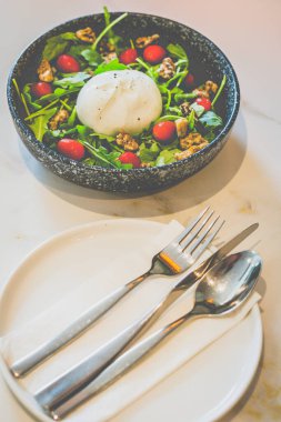 Kiraz domatesli, roka ve cevizli kremalı mozzarella burata roka üzerine biraz deniz tuzu serpiştirilmiş..