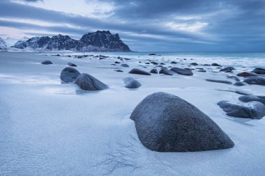 Gün batımı sırasında taşlarla deniz kıyısı. Norveç'te güzel doğal deniz manzarası