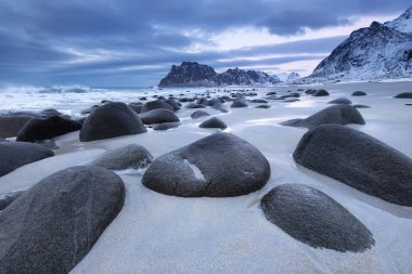 Gün batımı sırasında taşlarla deniz kıyısı. Norveç'te güzel doğal deniz manzarası