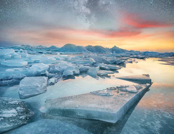 Ice on the ocean shore at the night time. Sea bay and stars at the night time. Milky way above ocean, Norway. Beautiful natural landscape in the Norway