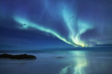 Aurora borealis Lofoten Adaları, Norveç. Okyanus üzerinde yeşil Kuzey ışıkları. Kutup ışıkları ile gece gökyüzü. Aurora ve su yüzeyinde yansıma ile gece kış manzarası. Norveç'te doğal arka plan