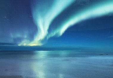 Aurora borealis Lofoten Adaları, Norveç. Okyanus üzerinde yeşil Kuzey ışıkları. Kutup ışıkları ile gece gökyüzü. Aurora ve su yüzeyinde yansıma ile gece kış manzarası. Norveç'te doğal arka plan