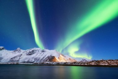 Aurora borealis Lofoten Adaları, Norveç. Dağlar yukarıda yeşil Kuzey ışıkları. Kutup ışıkları ile gece gökyüzü. Aurora ve su yüzeyinde yansıma ile gece kış manzarası. Norveç'te doğal arka plan