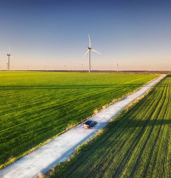 夕暮れ時の美しい夏の畑の道路の空中写真 田舎道での風景 風力発電 フィールドを介して道路 飛行ドローンから平面図です 旅行イメージ — ストック写真