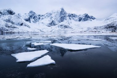 Dağ sırtı ve buz donmuş gölün yüzeyinde. Doğal peyzaj Lofoten Adaları, Norveç. Su ve dağlar gün batımı sırasında. Seyahat - resim