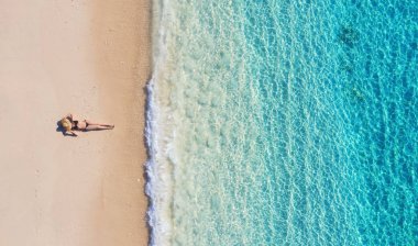 Bali, Endonezya sahilde bir kızın havadan görünümü. Tatil ve macera. Plaj ve turkuaz su. Plajda drone üst görünümü, masmavi deniz ve kız rahatlayın. Seyahat ve dinlenmek - görüntü