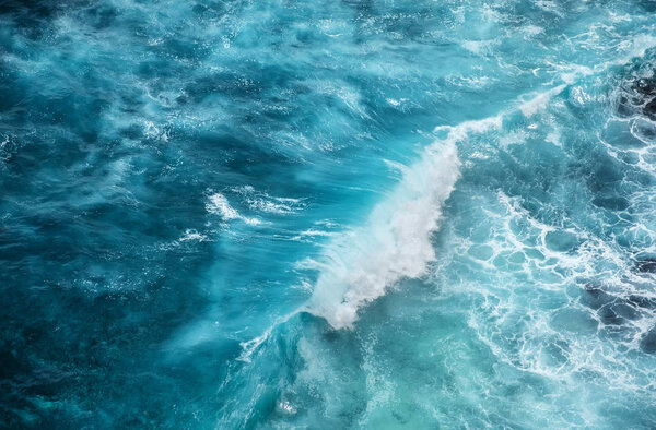 Waves and azure water as a background. View from high rock at the ocean surface. Natural summer seascape. Water background.