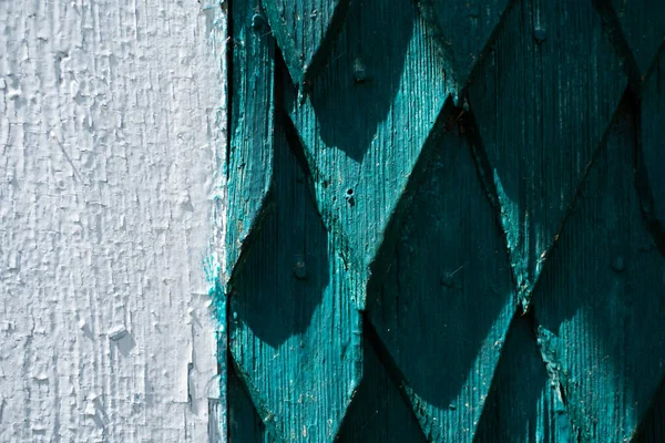 The wall of the house is made of old wood. Wooden details in the form of a rhombus. Background and texture of old painted wood.