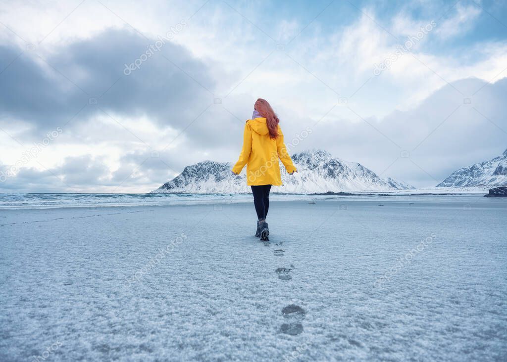 A traveler in a yellow raincoat. Skagsanden beach on Lofoten Islands, Norway. Journey and adventure. Winter landscape. Travel - image
