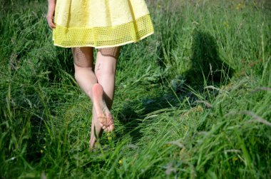 Erkek ile çıplak ayakla çimlerde yürüyor. Genç kadın açık yürüyüş, doğa, yeşil alanları ve mavi gökyüzü sahiptir.