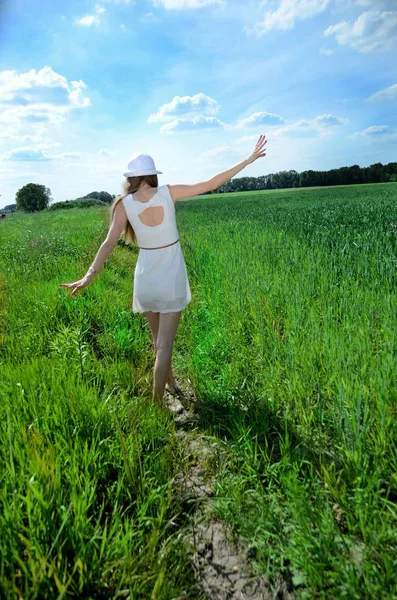 Yeşil tahıl alanıyla çevrili beyaz elbiseli Genç kadın. Erkek doğal sahne, yeşil alanları ve mavi gökyüzü.
