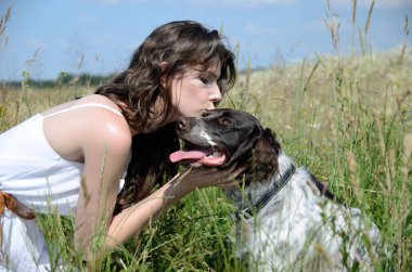 İle oturup onun en sevdiğim köpek çim ve çiçek çevrili beyaz elbise giyen kadın. Kırsal, yaz yürüyüş kadın modeli.