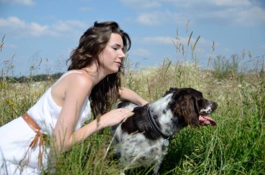 İle oturup onun en sevdiğim köpek çim ve çiçek çevrili beyaz elbise giyen kadın. Kırsal, yaz yürüyüş kadın modeli.