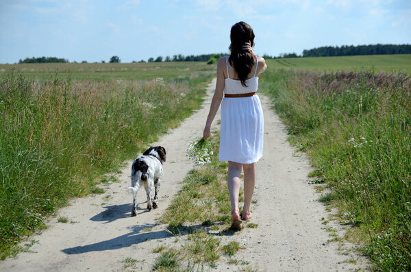 Женщина в белом платье гуляет со своей любимой собакой. Женская модель в сельской местности, летняя прогулка
.